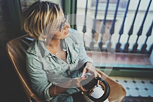 Smiling beautiful girl relaxing at home,playing music using smartphone and wearing sun glasses and modern headphones