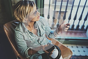 Smiling beautiful girl relaxing at home,playing music using smartphone and wearing sun glasses and modern headphones