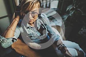 Smiling beautiful girl relaxing at home,playing music using smartphone and wearing sun glasses and modern headphones