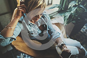 Smiling beautiful girl relaxing at home,playing music using smartphone and wearing sun glasses and modern headphones