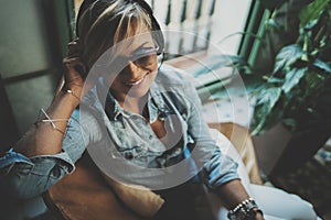 Smiling beautiful girl relaxing at home,playing music using smartphone and wearing sun glasses and modern headphones