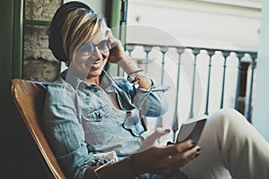 Smiling beautiful girl relaxing at home,playing music using smartphone and wearing sun glasses and modern headphones