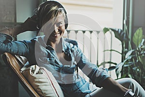 Smiling beautiful girl relaxing at home,playing music using smartphone and wearing sun glasses and modern headphones
