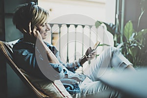 Smiling beautiful girl relaxing at home,playing music using smartphone and wearing sun glasses and modern headphones