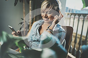 Smiling beautiful girl relaxing at home,wearing casual clothes,playing music,using smartphone and listening audio books