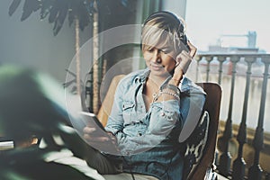 Smiling beautiful girl relaxing at home,wearing casual clothes,playing music,using smartphone and listening audio books