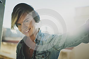 Smiling beautiful girl relaxing at home,wearing casual clothes,playing music,using smartphone and listening audio books