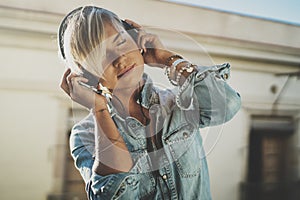 Smiling beautiful girl relaxing at home,wearing casual clothes,playing music,using smartphone and listening audio books