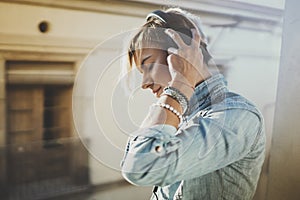 Smiling beautiful girl relaxing at home,wearing casual clothes,playing music,using smartphone and listening audio books