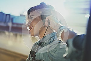 Smiling beautiful girl relaxing at home,wearing casual clothes,playing music,using smartphone and listening audio books