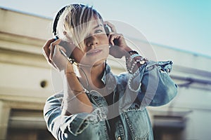 Smiling beautiful girl relaxing at home,wearing casual clothes,playing music,using smartphone and listening audio books