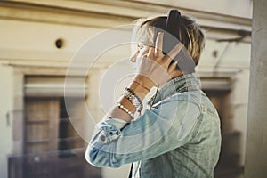 Smiling beautiful girl relaxing at home,wearing casual clothes,playing music,using smartphone and listening audio books