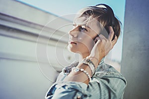 Smiling beautiful girl relaxing at home,wearing casual clothes,playing music,using smartphone and listening audio books