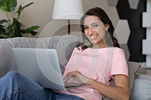 Smiling beautiful millennial indian arabic woman using computer.