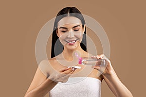 Smiling beautiful naked woman using micellar water and cotton pad