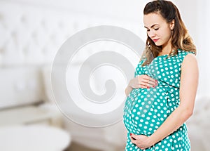 Smiling beautiful pregnant woman at home with big belly. Pregnancy and motherhood concept. Happy baby expectation. Interior