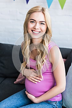 smiling beautiful pregnant woman sitting on sofa
