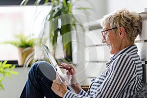 Smiling beautiful senior woman using digital tablet at home