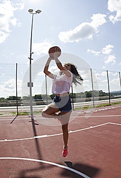 Smiling beautiful, sporty, fit, black woman from Africa.She jumps with the ball.