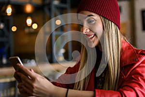 Smiling beautiful urban girl using smart-phone out in the cafeteria