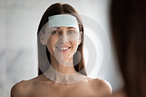 Smiling beautiful woman with anti wrinkle patch on forehead