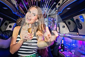 Smiling beautiful woman with champagne flute taking selfie on mo