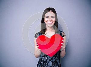 Smiling beautiful woman in dress holding red heart photo