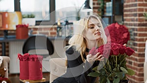 Smiling beautiful woman feeling loved on valentine day smelling elegant bouquet of roses