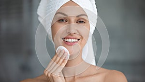 Smiling beautiful woman hold cotton pad cleansing face skin