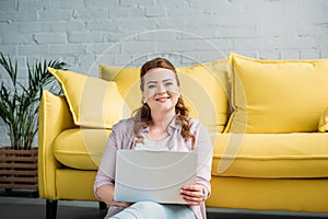 smiling beautiful woman holding laptop and looking at camera