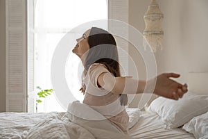 Smiling beautiful woman sitting in bed, stretching after awakening