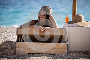 Smiling beautiful woman sunbathing in a bikini on a beach at tropical travel resort