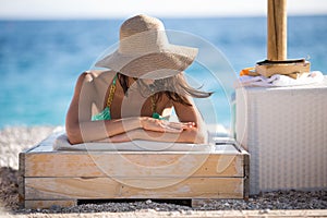 Smiling beautiful woman sunbathing in a bikini on a beach at tropical travel resort