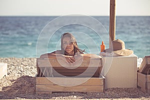 Smiling beautiful woman sunbathing in a bikini on a beach at tropical travel resort