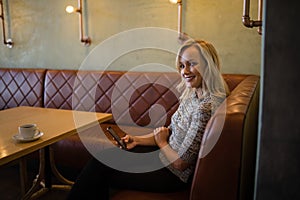 Smiling beautiful woman using mobile phone in restaurant