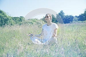 Smiling beautiful yoga girl meditating for openness in green environment photo