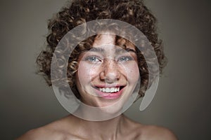 Smiling beautiful young freckled girl with curly hair, selective focus