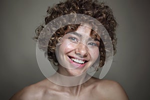 Smiling beautiful young freckled girl with curly hair, selective focus