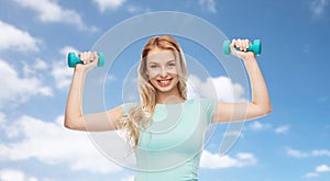 Smiling beautiful young sporty woman with dumbbell