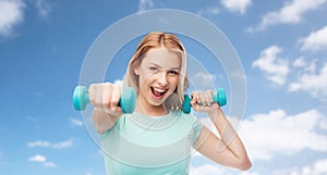 Smiling beautiful young sporty woman with dumbbell