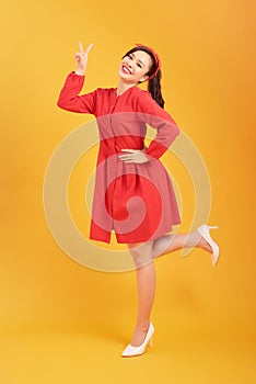 Smiling beautiful young woman in elegant red dress is holding hands on hip and looking away