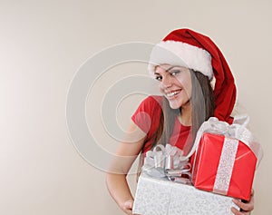 Smiling beautiful young woman in Santa hat with gifts for Christ