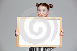 Smiling beautiful young woman showing blank whiteboard