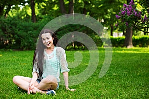 Smiling beautiful young woman sitting on grass.