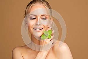 Smiling Beauty Model Smooth Skin with Mint. Woman Face and Body Health Care. Blond Girl with Wet Hair Holding Fresh Green Leaves