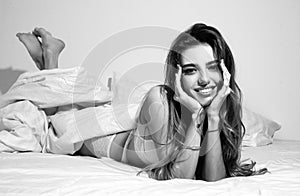 Smiling beauty woman laying in bed under a duvet in bedroom.