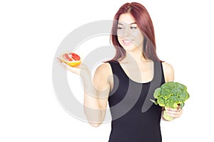 Smiling beauty woman looking at grapefruit and holding broccoli. Woman sitting on a diet. Vegan food.
