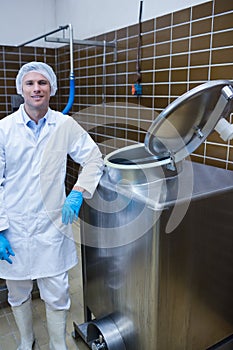 Smiling biologist leaning against storage tank