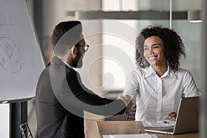 Smiling biracial businesswoman handshake male colleague at briefing