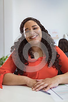 Smiling biracial businesswoman sitting at desk making video call in modern office